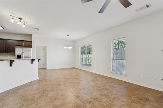 unfurnished living room with ceiling fan with notable chandelier