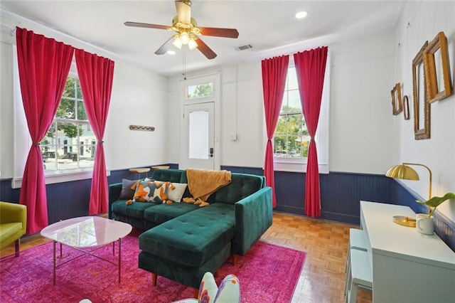 living room with ceiling fan, parquet floors, and a healthy amount of sunlight