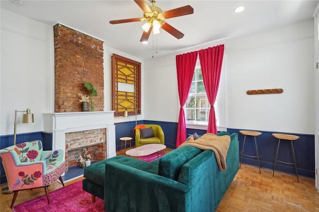 living area featuring ceiling fan, parquet floors, and a fireplace