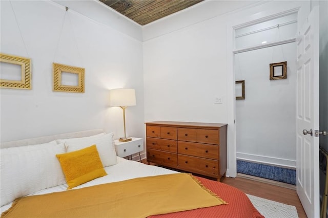 bedroom featuring wood-type flooring, wooden ceiling, and a closet