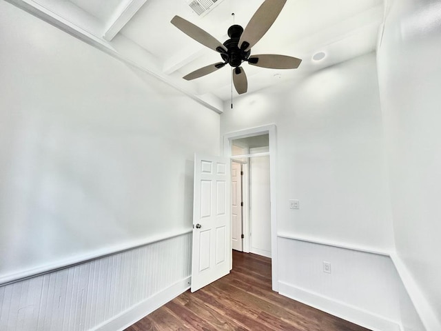 empty room featuring ceiling fan, beamed ceiling, and dark hardwood / wood-style floors