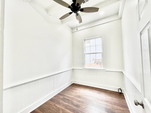 empty room featuring beam ceiling, ceiling fan, and dark wood-type flooring