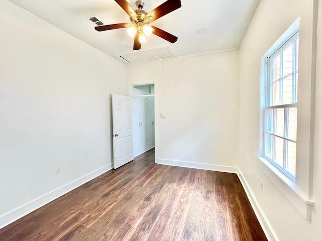 empty room with plenty of natural light, ceiling fan, and dark wood-type flooring