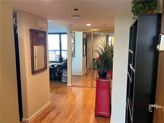 hall with a textured ceiling and light hardwood / wood-style floors