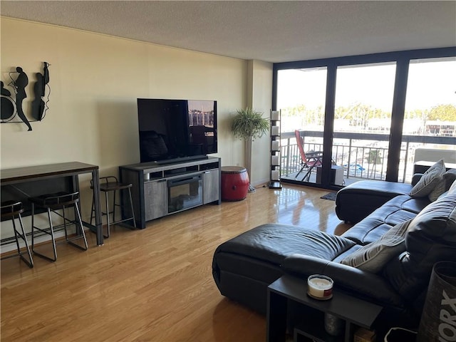 living room with floor to ceiling windows, a textured ceiling, and light wood-type flooring