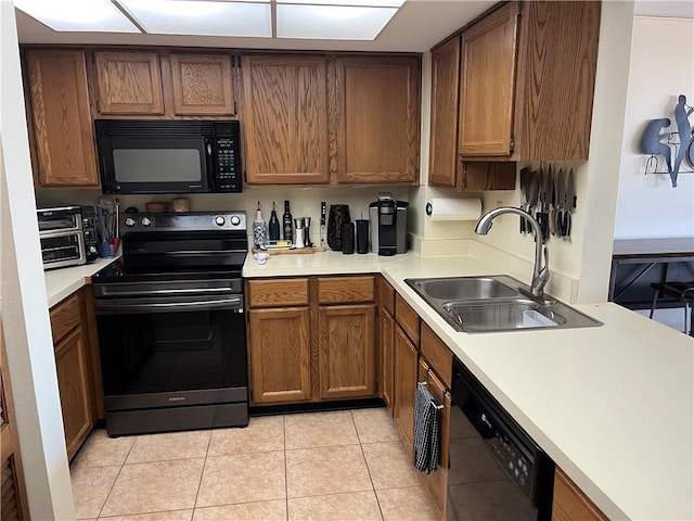 kitchen featuring black appliances, light tile patterned floors, and sink