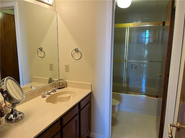 full bathroom featuring combined bath / shower with glass door, vanity, toilet, and tile patterned flooring