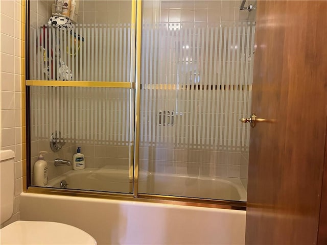 bathroom with toilet and combined bath / shower with glass door