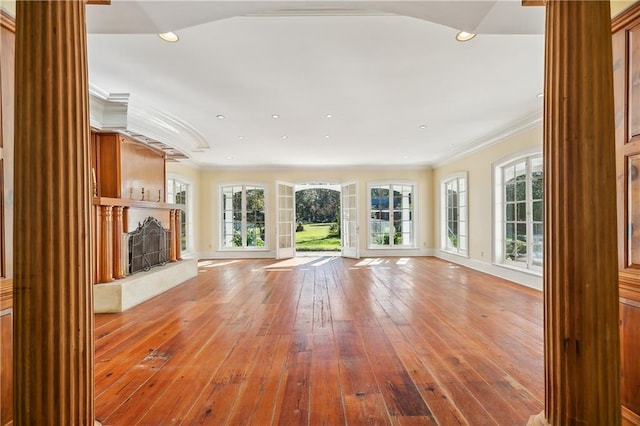 unfurnished living room featuring hardwood / wood-style floors, ornamental molding, and a wealth of natural light