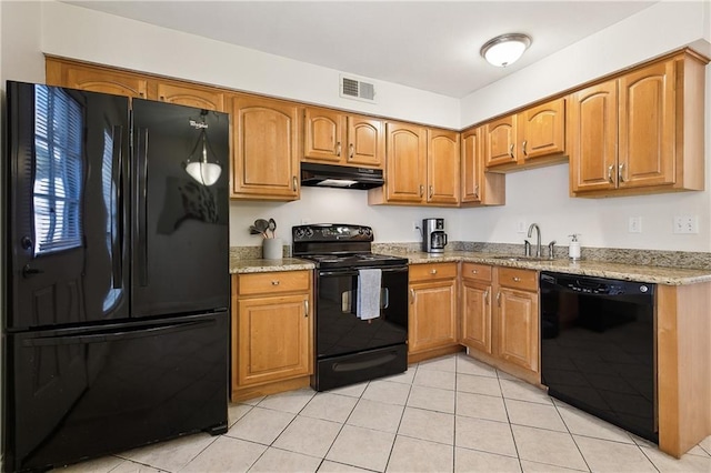 kitchen featuring light stone countertops, sink, light tile patterned flooring, and black appliances