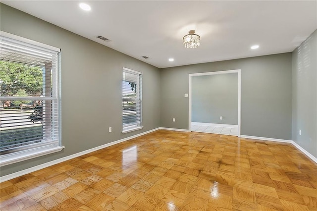 spare room with an inviting chandelier and light parquet floors