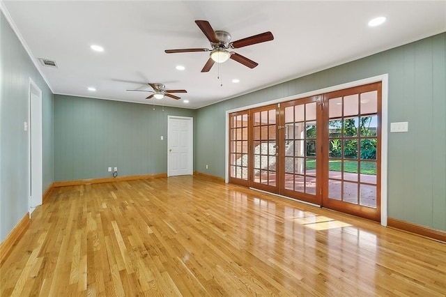 empty room featuring ceiling fan, light wood-type flooring, crown molding, and french doors