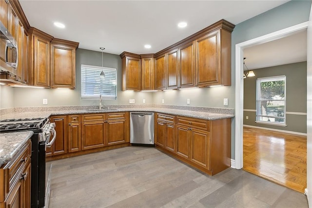 kitchen with pendant lighting, sink, light hardwood / wood-style flooring, light stone countertops, and appliances with stainless steel finishes