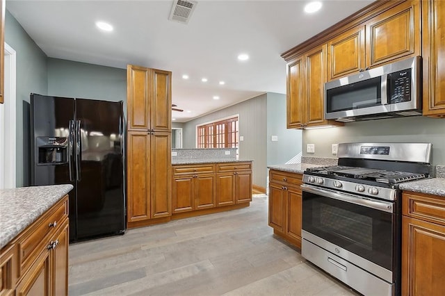 kitchen with light wood-type flooring, stainless steel appliances, and light stone counters