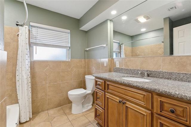 full bathroom with a wealth of natural light, vanity, tile walls, tile patterned flooring, and toilet