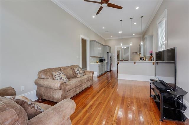 living room featuring ceiling fan, light wood-type flooring, and ornamental molding