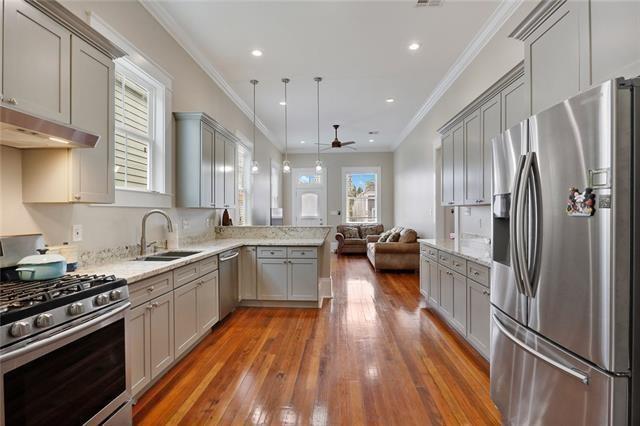 kitchen with kitchen peninsula, gray cabinetry, stainless steel appliances, ceiling fan, and decorative light fixtures