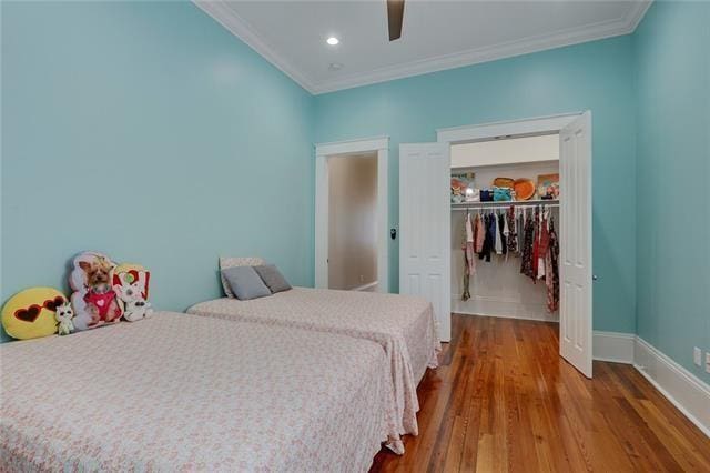 bedroom featuring ceiling fan, a closet, hardwood / wood-style floors, and ornamental molding