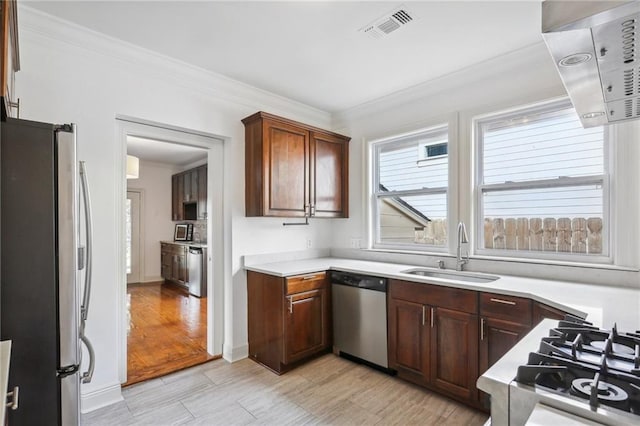 kitchen featuring crown molding, sink, light wood-type flooring, and appliances with stainless steel finishes