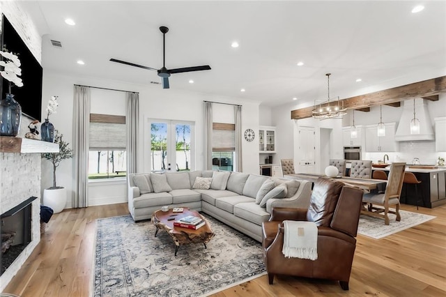 living room with ceiling fan, light wood-type flooring, a fireplace, and french doors