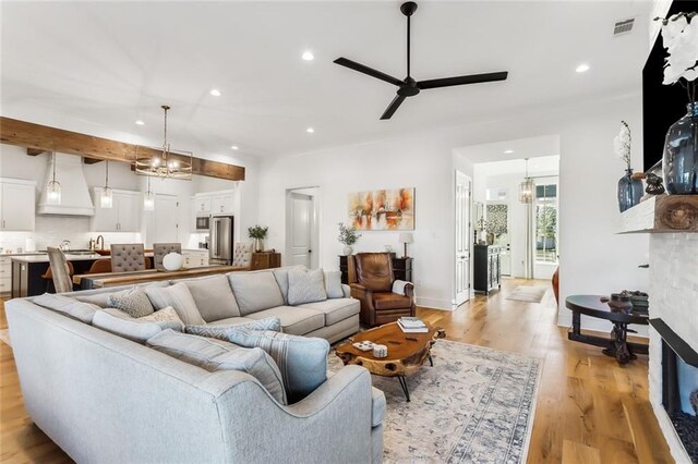 living room featuring ceiling fan with notable chandelier and light hardwood / wood-style floors