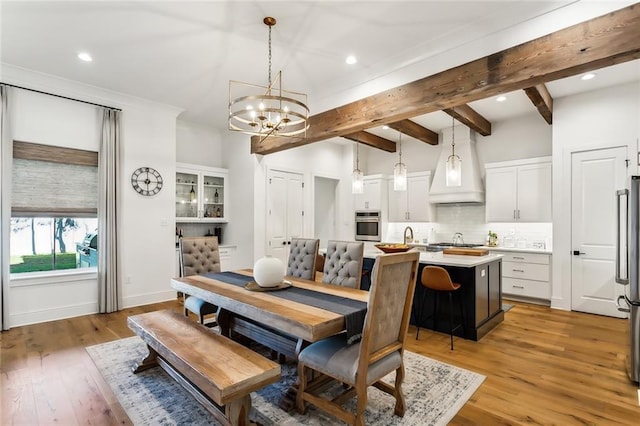 dining space featuring a chandelier, light hardwood / wood-style floors, and beamed ceiling