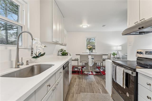 kitchen with appliances with stainless steel finishes, light hardwood / wood-style floors, white cabinetry, and sink