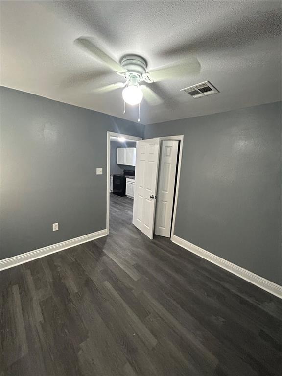 empty room featuring ceiling fan, dark hardwood / wood-style flooring, and a textured ceiling