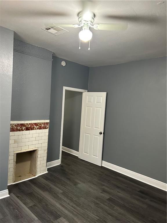 unfurnished living room with a fireplace, dark hardwood / wood-style flooring, and ceiling fan