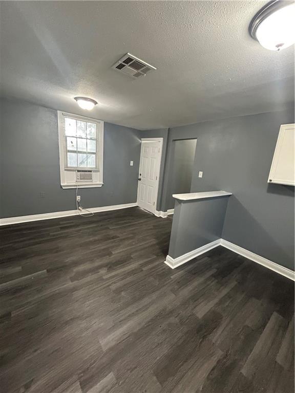 unfurnished room with cooling unit, dark hardwood / wood-style flooring, and a textured ceiling