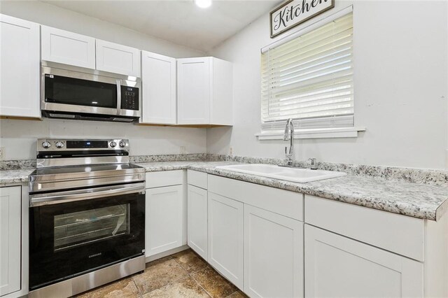 kitchen featuring stainless steel appliances, white cabinetry, and sink