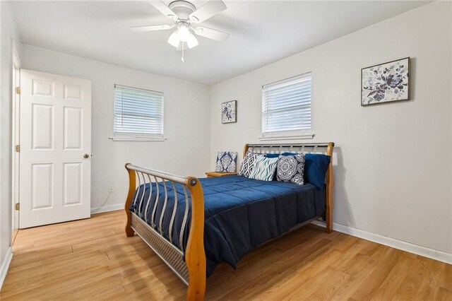 bedroom featuring ceiling fan, light wood-type flooring, and multiple windows