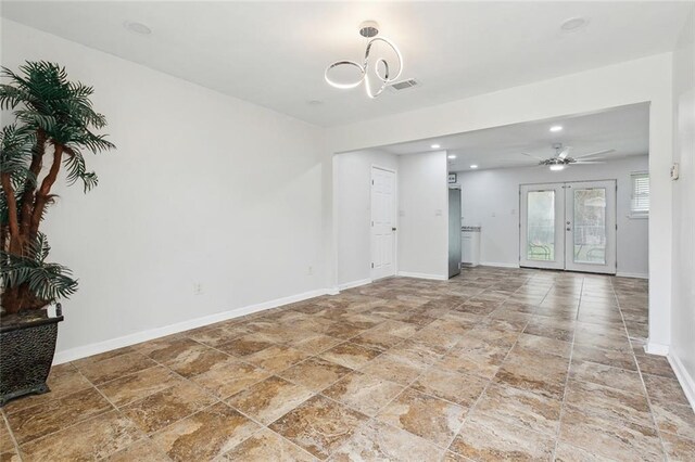 unfurnished living room with ceiling fan with notable chandelier and french doors