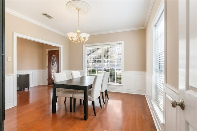 dining area featuring wood-type flooring, an inviting chandelier, and crown molding