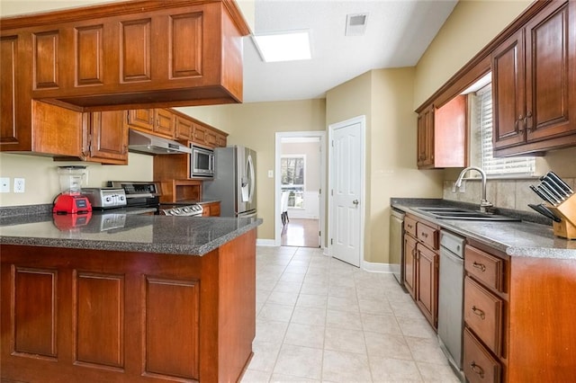 kitchen with kitchen peninsula, appliances with stainless steel finishes, light tile patterned floors, and sink