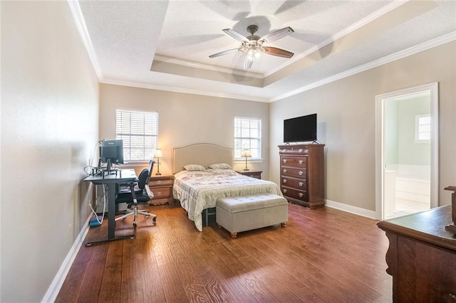 bedroom featuring a raised ceiling, ensuite bath, hardwood / wood-style flooring, ceiling fan, and ornamental molding