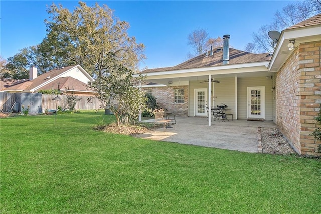 rear view of house with ceiling fan, a patio area, and a lawn