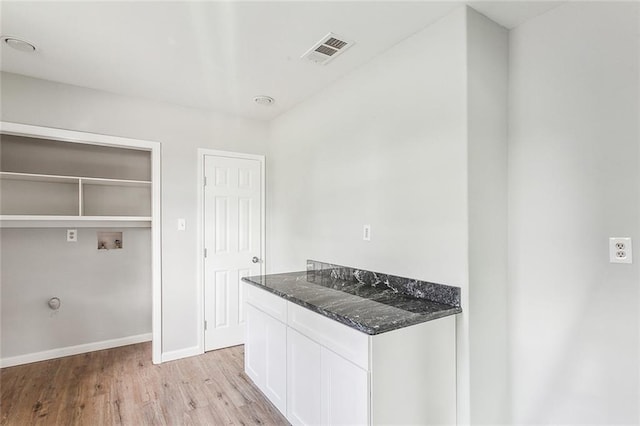 kitchen featuring white cabinets, light hardwood / wood-style flooring, and dark stone countertops