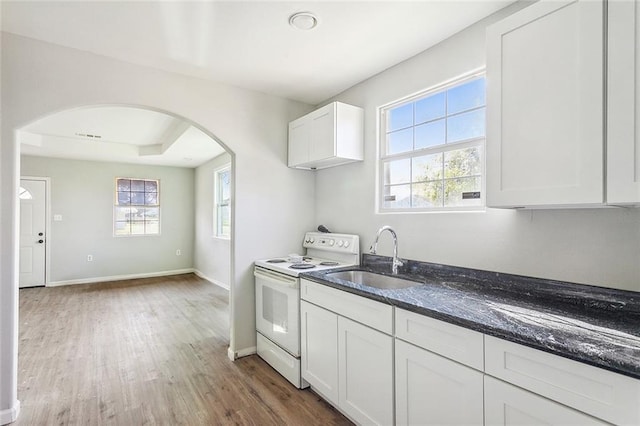 kitchen featuring white range with electric cooktop, sink, white cabinets, dark stone counters, and hardwood / wood-style floors