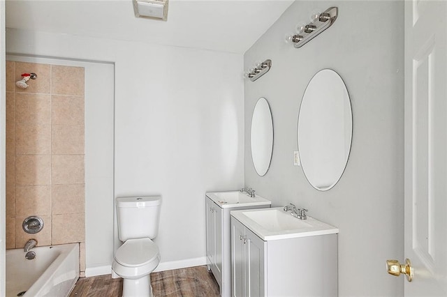 full bathroom featuring wood-type flooring, toilet, tiled shower / bath combo, and vanity