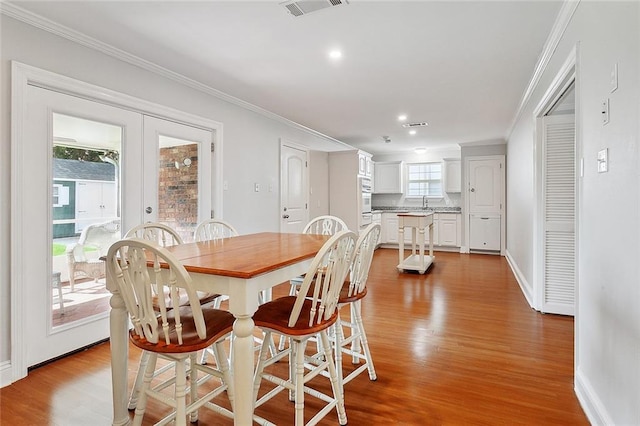 dining space with light wood-type flooring, french doors, and ornamental molding