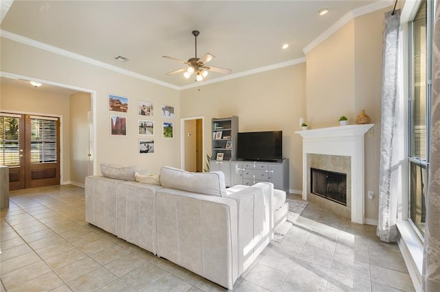 living room with a tile fireplace, ceiling fan, french doors, light tile patterned flooring, and ornamental molding