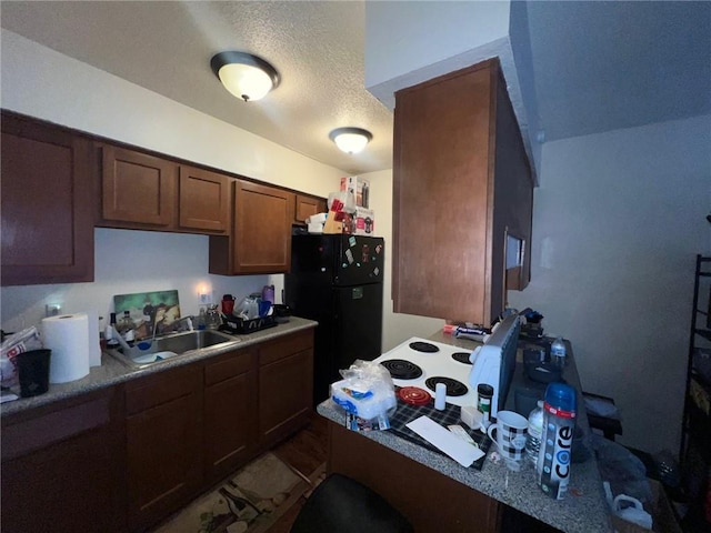 kitchen with black refrigerator, light tile patterned floors, a textured ceiling, and sink