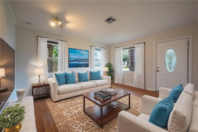 living room featuring a wealth of natural light, ornamental molding, and light wood-type flooring