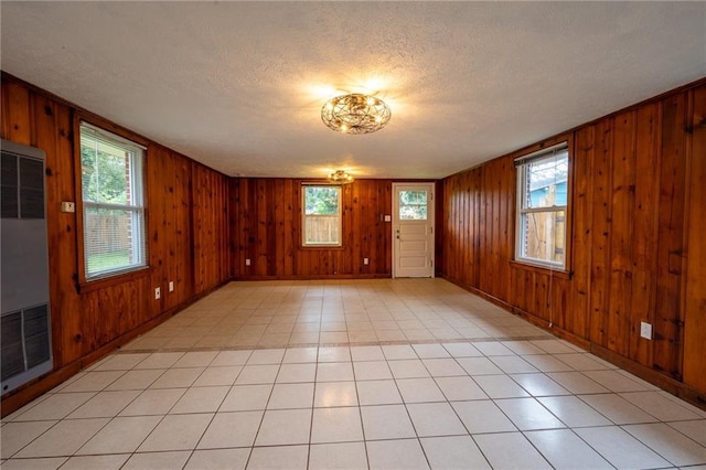 tiled spare room with a textured ceiling and wooden walls