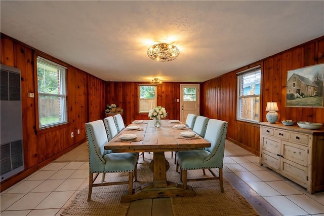 dining room featuring light tile patterned floors and wood walls