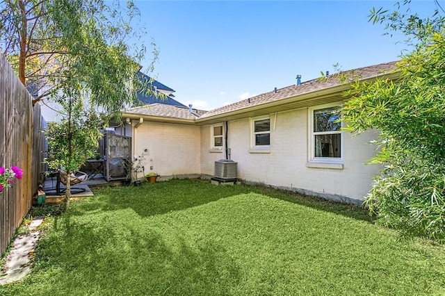 rear view of property featuring cooling unit and a yard