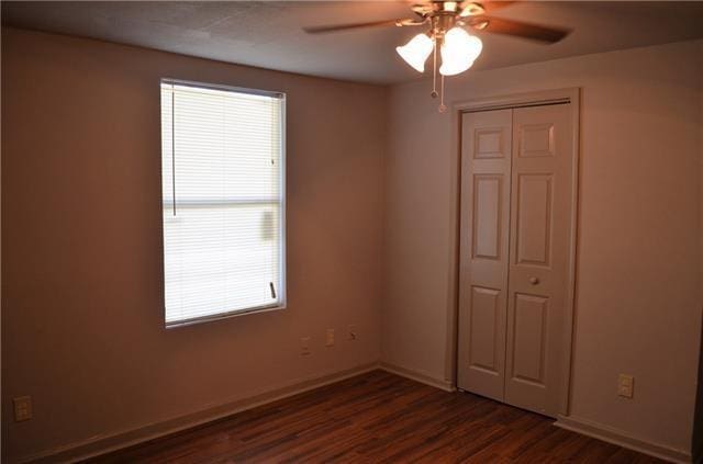 unfurnished bedroom featuring a closet, dark hardwood / wood-style floors, and ceiling fan