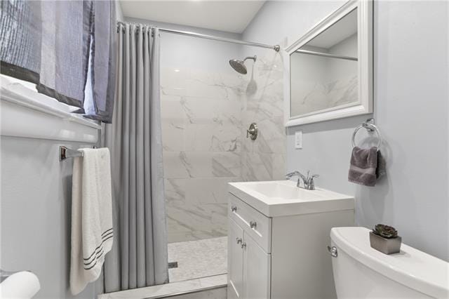 bathroom featuring vanity, toilet, and tiled shower