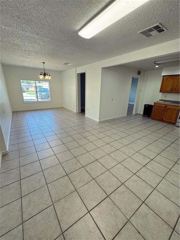unfurnished living room featuring a notable chandelier, a textured ceiling, visible vents, and light tile patterned floors